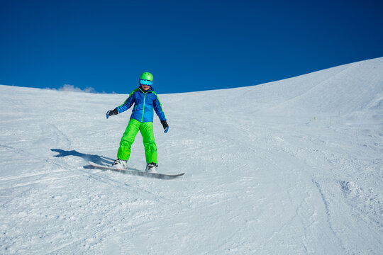 Front view action photo of boy snowboard down mountain slope