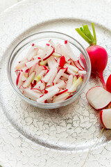 Radish cut into strips in a glass cup on a silver tray.