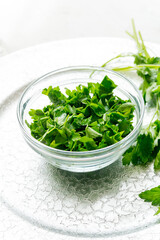 Sliced parsley in a glass cup on a silver tray