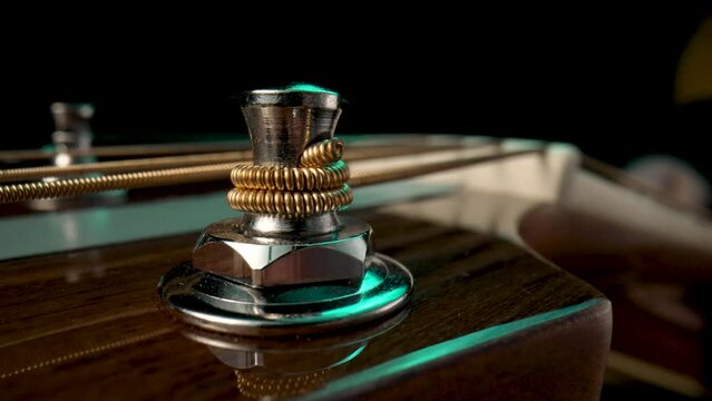 Wooden guitar's headstock with metal tuning pegs and string on black background. Pegs are twisted for tensioning and tuning the sound of the strings. Acoustic guitar headstock close up macro.