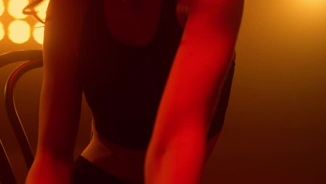 Unknown woman performing erotic moves sitting chair strip club close up.