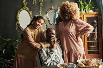 Portrait of happy African family of three smiling at camera while having family dinner at home