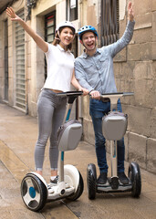 Fototapeta na wymiar young couple guy and girl walking on self-propelled vehicles in streets of european city