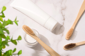 Top view on natural bamboo toothbrushes, mineral toothpowder and toothpaste tube on white table background. Natural bath products, organic dentifrice. Mockup image