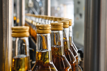 Bottles of golden alcohol with caps transported by conveyor