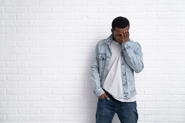 Obraz premium Portrait young upset african black man wearing denim jeans jacket against brick with wall outdoors with copyspace