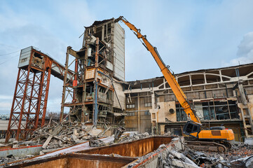 Fototapeta na wymiar Destroyer excavator with large manipulator near factory