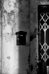 Black mailbox on chipped facade next to door