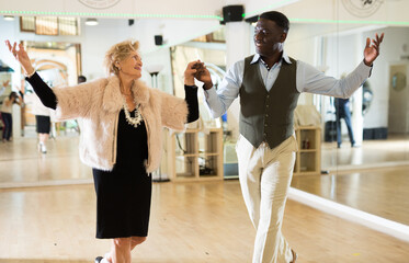 Elderly woman learning ballroom dancing in pair in dance studio - obrazy, fototapety, plakaty