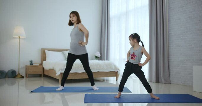 Asian mother and daughter  doing yoga together at home