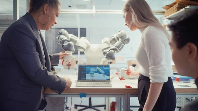 Diverse Computer Science Specialists Standing Near Black Chief Engineer and Developing Programme for Motion of Robotic Arm. Education and Innovative Technologies Concept. Moving Shot