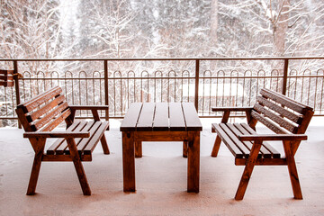 Plakat A table and benches in the snow on a snow-covered veranda.