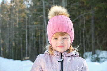 cute girl on a sunny winter day against the backdrop of snow and forest