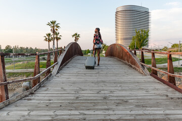 woman with face mask cross a wooden bridge with suitcase