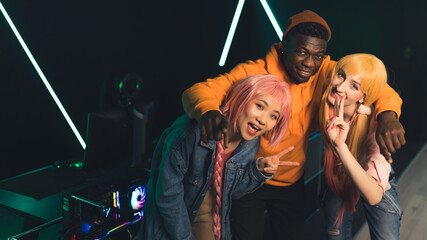 Three interracial young adults in casual wear standing, looking at camera, and smiling. Teammates are about to play a game together in an Internet cafe. Modern leisure time. High quality photo