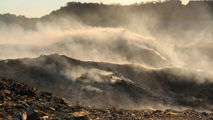 Burning pile of garbage at dump ground or landfill releasing toxic smoke in environment and...