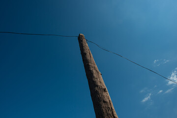 Old wooden pole and wires for communication against the blue sky.