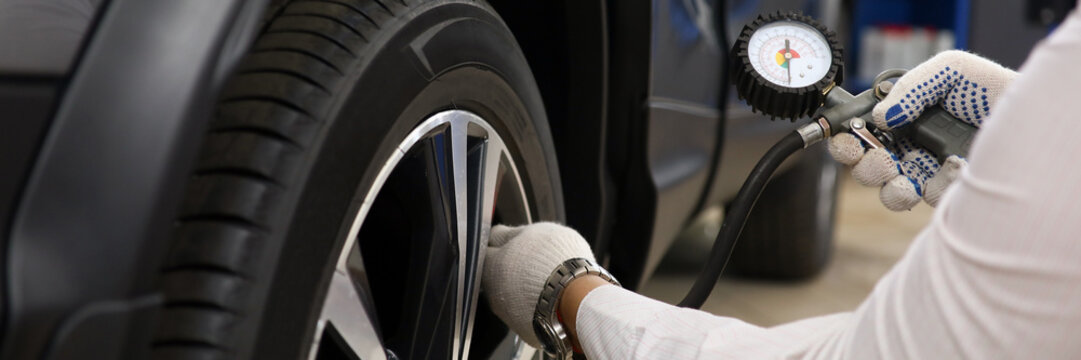 Technician checks tire pressure of car closeup