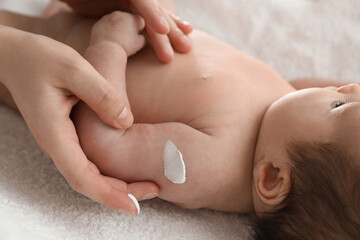 Fototapeta na wymiar Mother applying body cream on her little baby, closeup