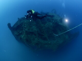 scuba divers exploring old ship wreck with torch light underwater from 1 world war ww1 wreck ocean...