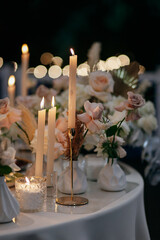 Wedding decor at the restaurant. Beautiful table setting with flowers and burning candles. 