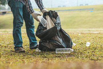 A man is picking up trash in a park, not throwing trash in the trash can ruin the beauty of the garden area and also cause global warming and harm animals. Concept of cleanliness in public areas.