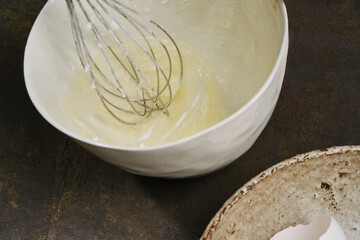 Kneading and whisking the liquid eggs with a mixer. Process of cooking meringue in a white bowl. Whipping cream with a whisk. Shallow depth of field