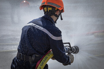 jeune pompier Français qui tient une lance à incendie lors d'un exercice