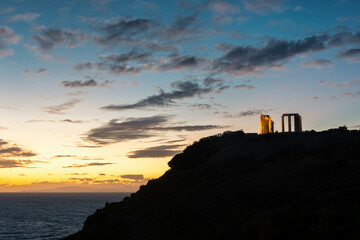 Beautiful sunset over the cliff of The Temple of Poseidon at Cape Sounion, over the Aegean Sea Greece