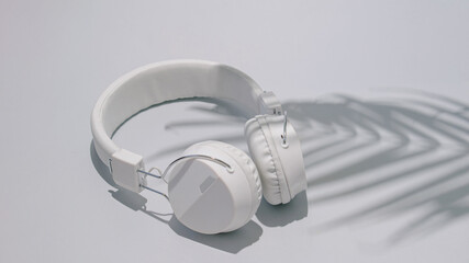 Headphones white with palm tree shadow. Summer day on a beach concept idea. Relax vacation on a sunny day