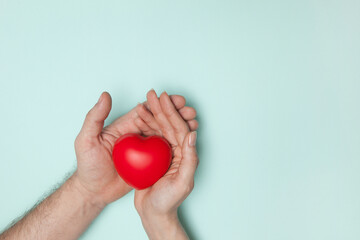 Man and woman hands holding red heart, health care, donate and family insurance concept, world heart day, world health day, CSR responsibility, adoption foster family, hope, gratitude, kind, concept.