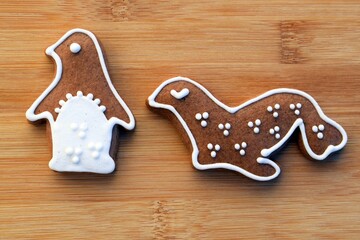 Cute gingerbread sea lion and penguin decorated with white icing, wooden background