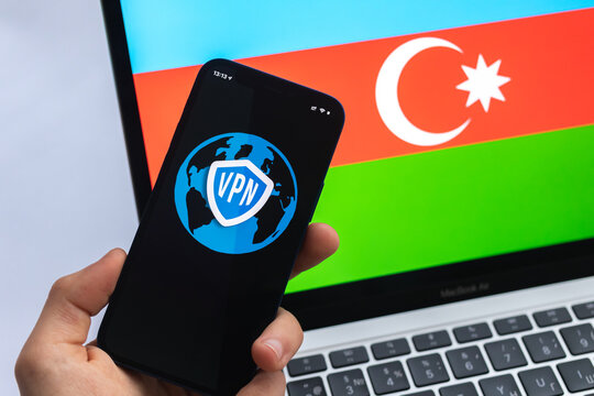 VPN in Azerbaijan. Secure and safe internet concept. Privacy. Hand with mobile phone and VPN application. Flag and laptop on the background - Powered by Adobe