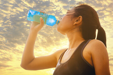 Silhouette of young man runner with a bottle of water freshness after training outdoor workout.