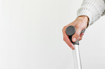 Retired woman holding metal walking stick in hand. Medical and healthcare concept. Copy space