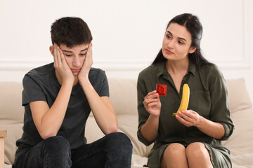 Mother talking with her teenage son about contraception at home. Sex education concept