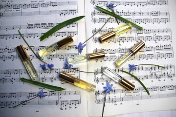 perfume aroma bottles with golden caps and smell, blue spring flowers on music note background