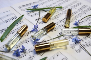 perfume aroma bottles with golden caps and smell, blue spring flowers on music note background