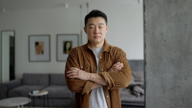 Concentrated Asian man wearing casual cloth looking at the camera at home