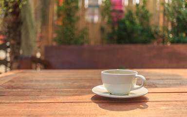 cup of coffee on wooden table in morning sun