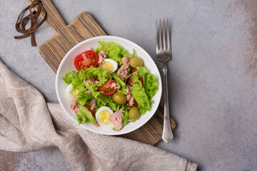 Healthy tuna salad with fresh lettuce, cherry tomatoes, quail egg and olives in bowl