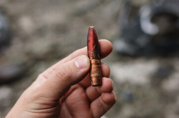 Close-up of human hand holding a large-caliber 12.7mm armor-piercing incendiary bullet