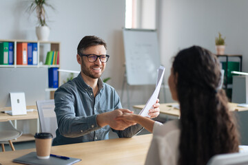 Happy personnel manager and female job applicant shaking hands after successful employment...