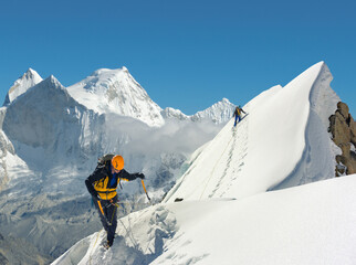 Naklejka na ściany i meble Mountaineering team roped up traversing steep ridge high up in the mountains