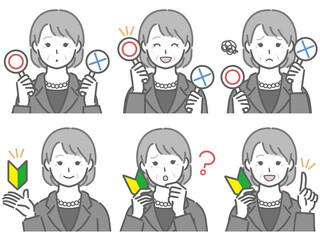 〇✕マークや初心者マークを持つスーツの高齢女性