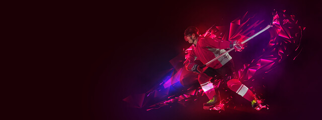 Young man, professional hockey player in protective uniform training isolated on dark background...