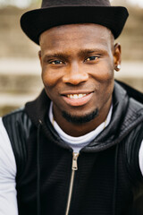 Portrait of a smiling handsome young black male wearing a black hat