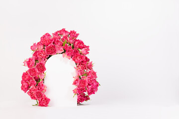 Elegant framing of arch of fresh little roses as abstract podium on white stage for presentation...