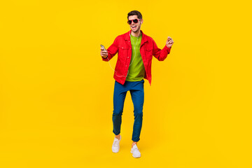 Fototapeta na wymiar Full body photo of funky young guy dance listen music wear glasses shirt pants sneakers isolated on yellow background