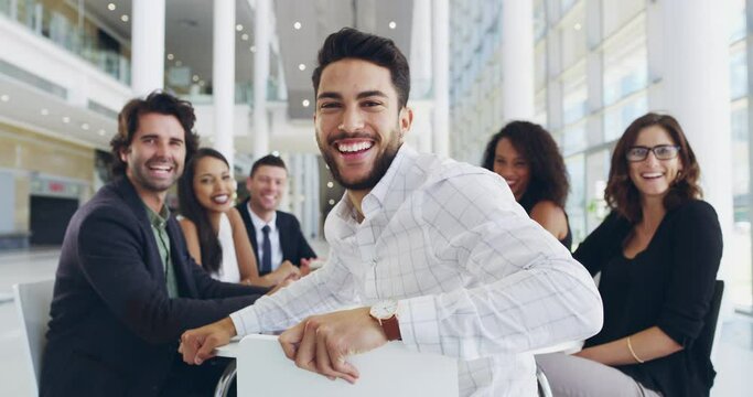 Positivity always leads to success. businessman smiling in an office during a meeting with his colleagues in the background. Portrait of cheerful young businessman smiling in a meeting with colleagues